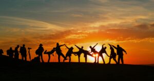 Group of people silhouetted against a vibrant sunset, showcasing unity and joy.