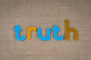 The word 'truth' in colorful felt letters on a burlap background.