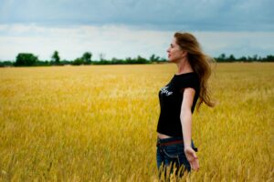 A woman enjoys a serene moment in a golden wheat field, feeling the freedom of nature.